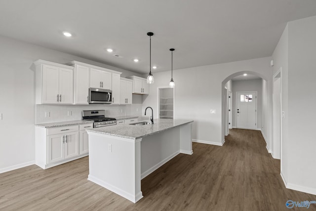 kitchen with stainless steel appliances, sink, a kitchen island with sink, and white cabinets