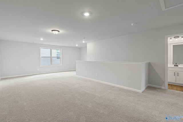 spare room with sink and light colored carpet