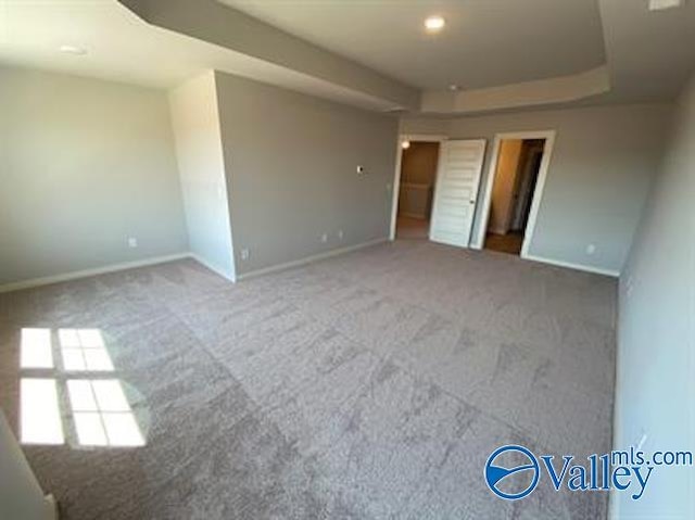 carpeted empty room featuring a tray ceiling