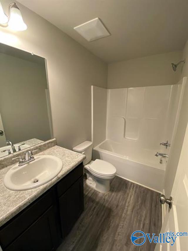 full bathroom featuring wood-type flooring, toilet, bathing tub / shower combination, and vanity