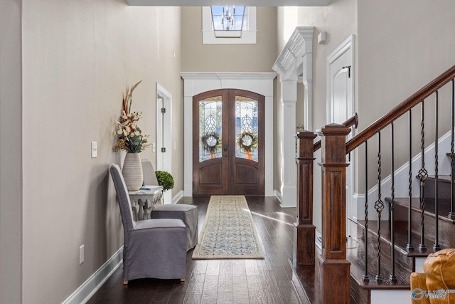 foyer entrance featuring a wealth of natural light, dark wood-style floors, a high ceiling, and stairs
