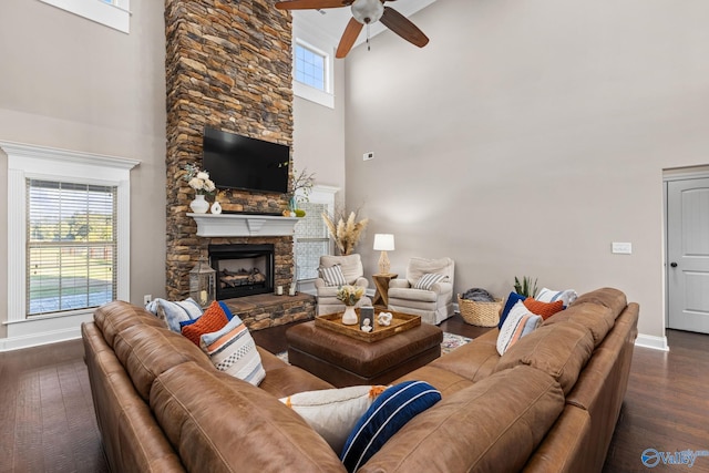 living room featuring baseboards, a fireplace, a high ceiling, ceiling fan, and wood finished floors