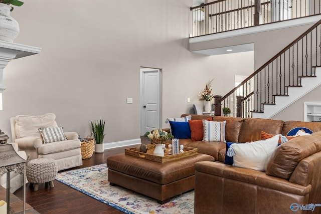 living room featuring baseboards, a towering ceiling, wood finished floors, and stairs