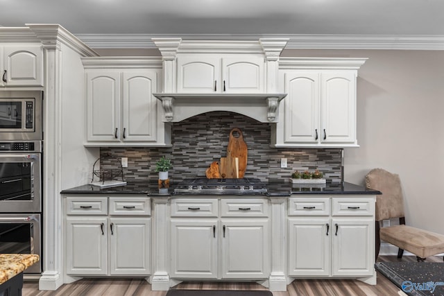 kitchen featuring dark stone counters, white cabinets, appliances with stainless steel finishes, wood finished floors, and decorative backsplash