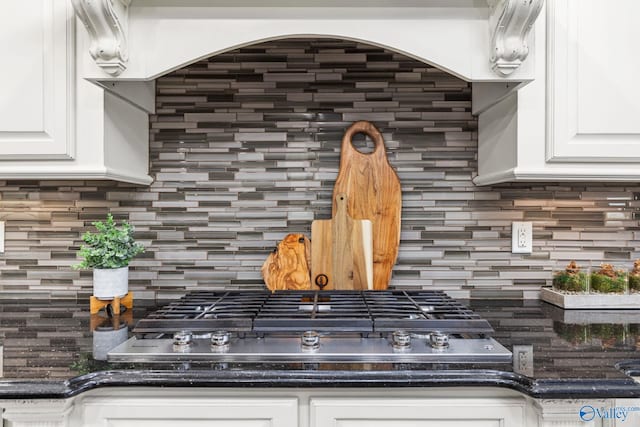 interior details featuring backsplash, white cabinets, and stainless steel gas stovetop