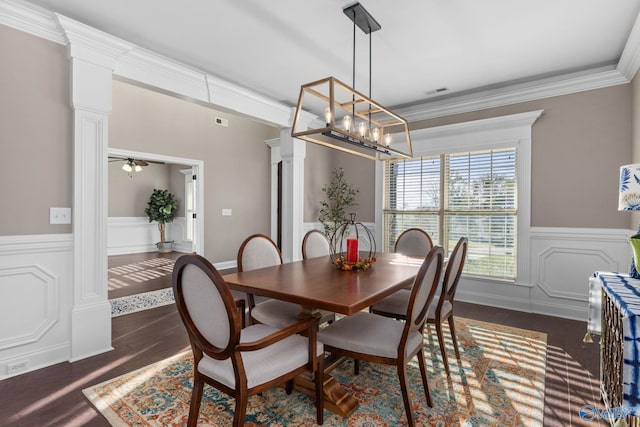 dining room featuring dark wood-style floors, crown molding, a wainscoted wall, decorative columns, and ceiling fan with notable chandelier