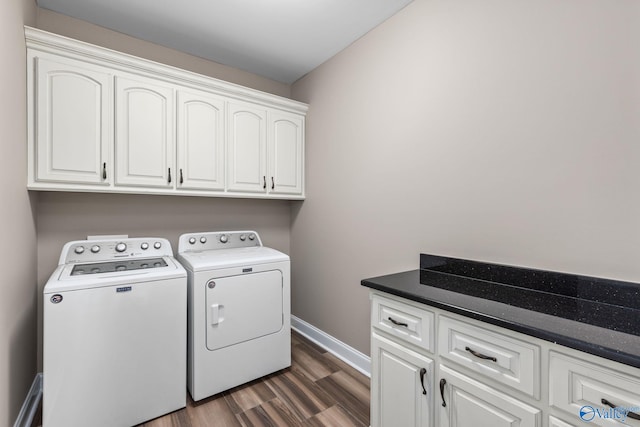 washroom with dark wood finished floors, baseboards, washing machine and clothes dryer, and cabinet space