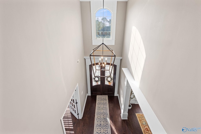 foyer with a high ceiling, wood finished floors, french doors, a notable chandelier, and baseboards