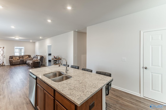 kitchen featuring sink, dishwasher, a breakfast bar area, a kitchen island with sink, and hardwood / wood-style flooring