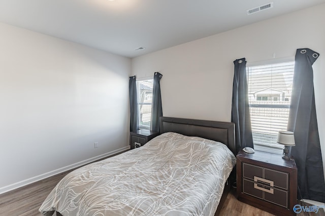 bedroom featuring multiple windows and dark wood-type flooring