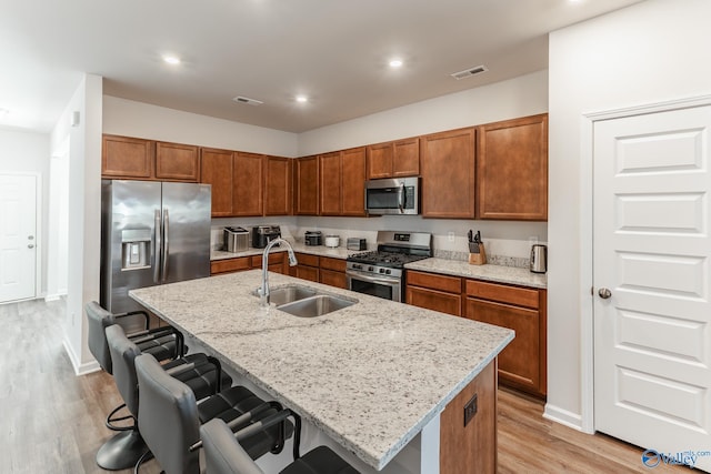 kitchen with sink, a kitchen bar, a kitchen island with sink, and appliances with stainless steel finishes