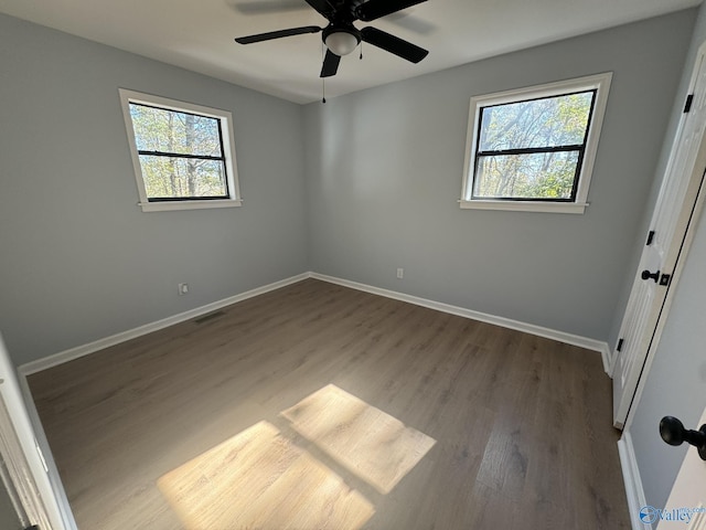 empty room featuring hardwood / wood-style flooring, ceiling fan, and a healthy amount of sunlight