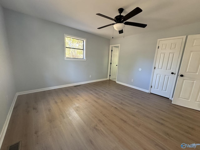 unfurnished bedroom featuring dark wood-type flooring, ceiling fan, and a closet