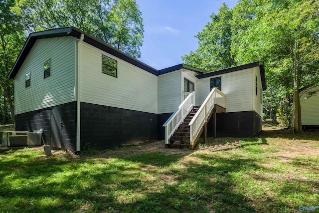 back of house with a yard and central air condition unit