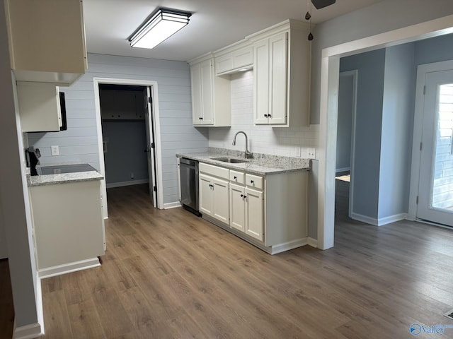 kitchen featuring sink, stainless steel dishwasher, white cabinets, and light stone countertops