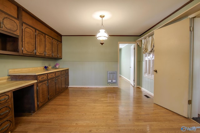 kitchen featuring heating unit, crown molding, dark brown cabinets, hanging light fixtures, and light hardwood / wood-style floors