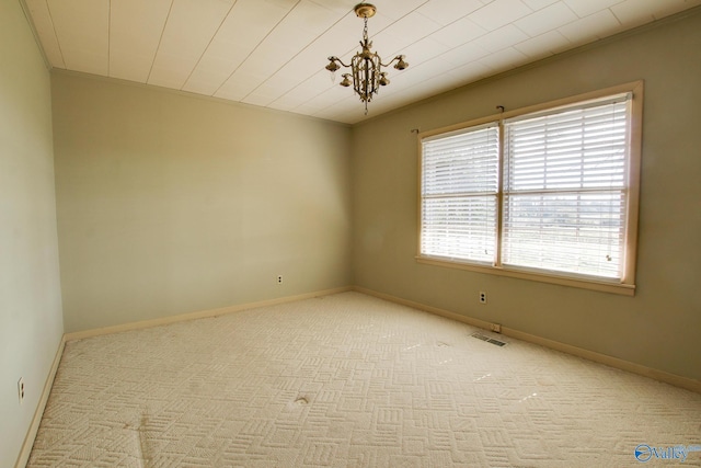 empty room featuring light colored carpet and a chandelier