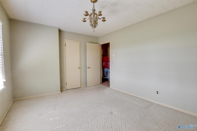 spare room with ornamental molding, a chandelier, and light carpet