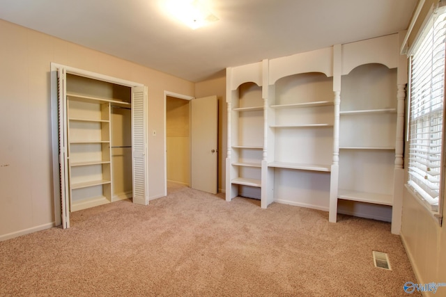 unfurnished bedroom featuring light colored carpet, multiple windows, and two closets