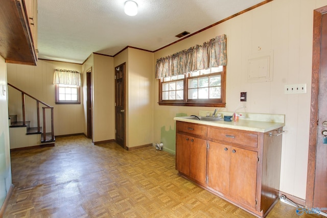 kitchen featuring crown molding, light parquet flooring, sink, and a textured ceiling