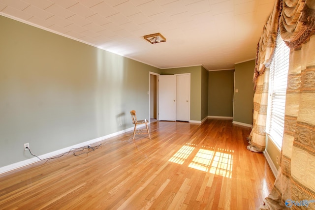 empty room featuring ornamental molding, plenty of natural light, and light hardwood / wood-style flooring