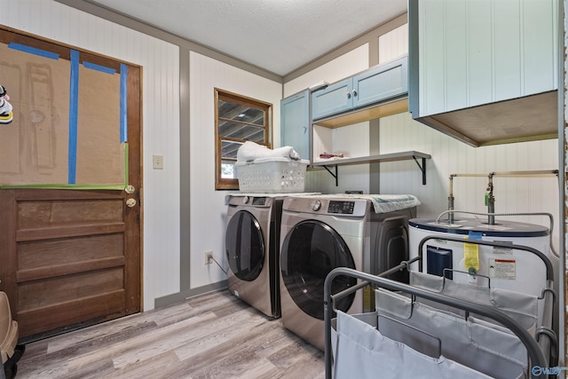 washroom with cabinets, washer and clothes dryer, a textured ceiling, and light wood-type flooring