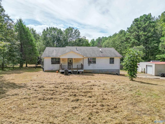 view of front of house featuring a garage, a front lawn, and an outbuilding