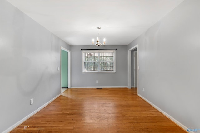 empty room with an inviting chandelier and light hardwood / wood-style flooring