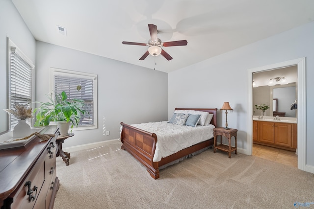 bedroom featuring light carpet, connected bathroom, sink, and ceiling fan