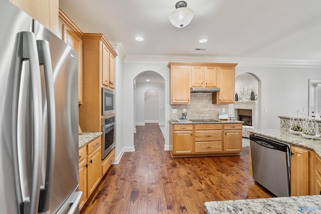 kitchen with appliances with stainless steel finishes, backsplash, dark hardwood / wood-style flooring, ornamental molding, and light stone counters