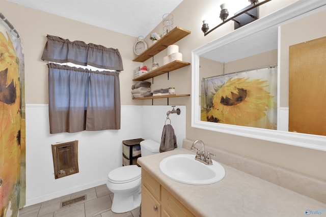 bathroom featuring toilet, vanity, tile patterned floors, and heating unit