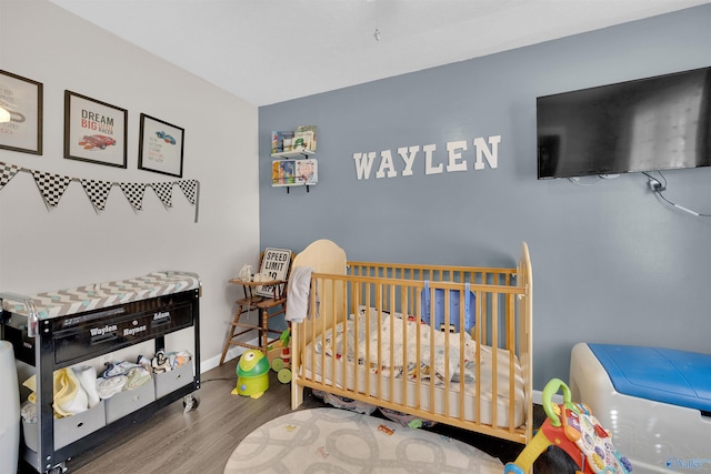 bedroom featuring hardwood / wood-style floors and a crib