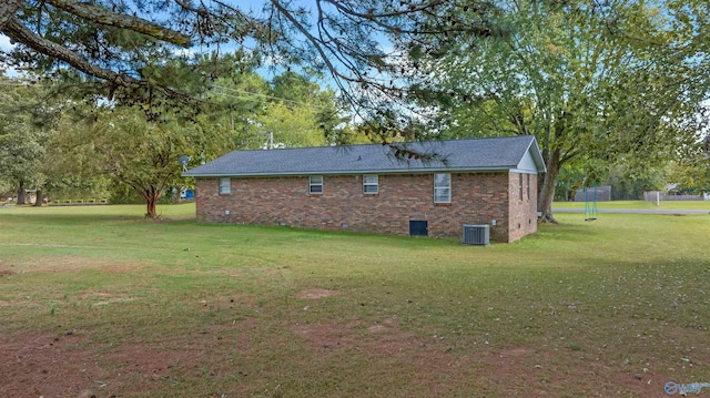 view of side of home with central air condition unit and a yard