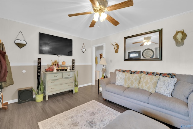 living room with ornamental molding, dark wood-type flooring, and ceiling fan