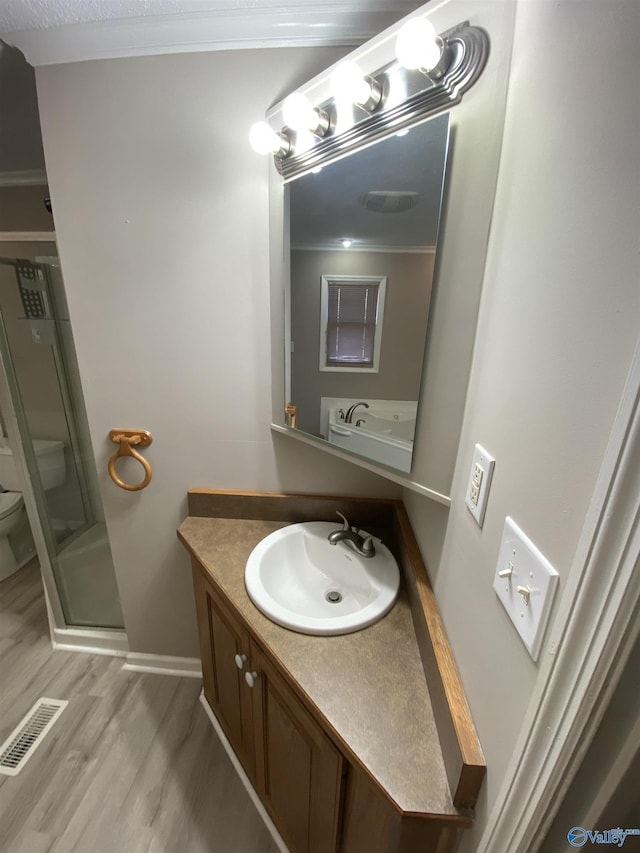 bathroom with an enclosed shower, hardwood / wood-style floors, toilet, vanity, and ornamental molding