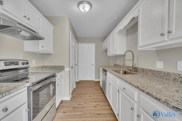 kitchen featuring white cabinetry, under cabinet range hood, a sink, light wood finished floors, and appliances with stainless steel finishes