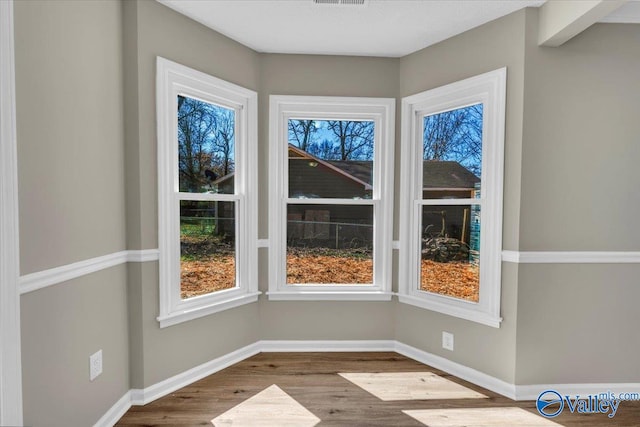 spare room featuring baseboards, dark wood-style floors, and visible vents
