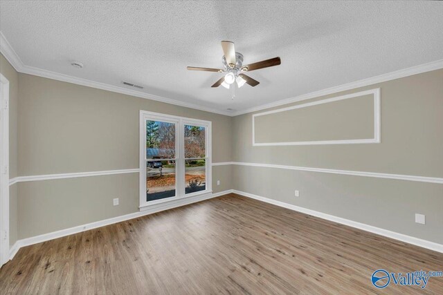 spare room with visible vents, ceiling fan, wood finished floors, and ornamental molding