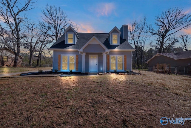 cape cod-style house featuring a chimney and fence