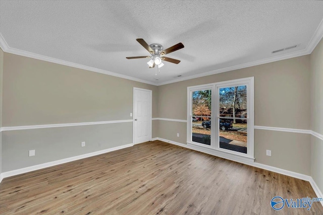 empty room with ornamental molding, baseboards, ceiling fan, visible vents, and wood finished floors