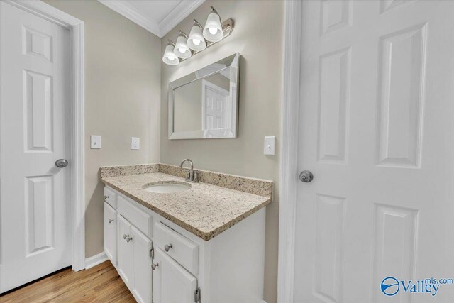 bathroom featuring baseboards, crown molding, wood finished floors, and vanity