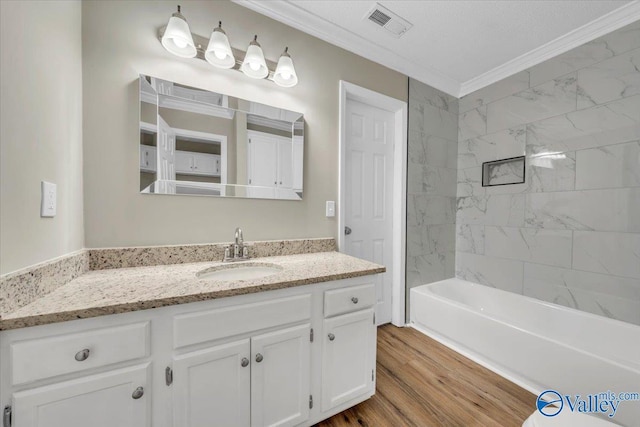 full bathroom with vanity, shower / bath combination, crown molding, visible vents, and wood finished floors