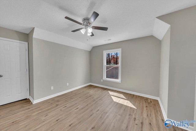 empty room featuring lofted ceiling, wood finished floors, ceiling fan, and a textured ceiling