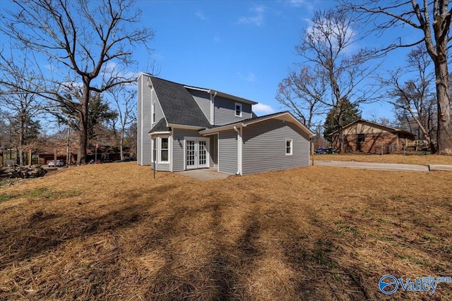 rear view of property with french doors, roof with shingles, and a lawn