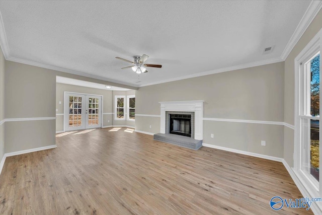 unfurnished living room featuring visible vents, a brick fireplace, ceiling fan, wood finished floors, and french doors