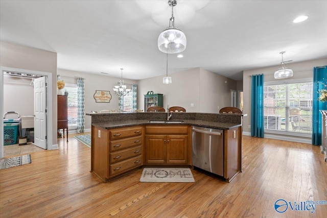 kitchen with decorative light fixtures, brown cabinets, light wood-type flooring, dishwasher, and a sink