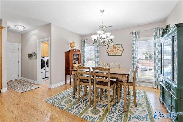 dining space with visible vents, washing machine and dryer, baseboards, light wood-type flooring, and a notable chandelier
