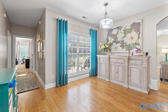 dining area with visible vents, arched walkways, light wood-style flooring, and baseboards
