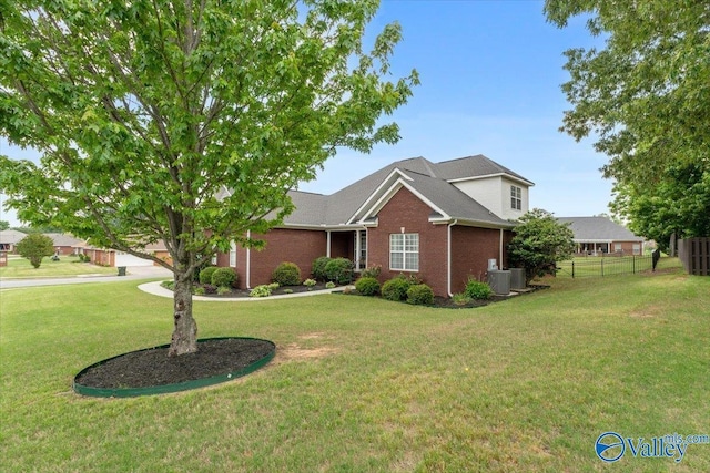 view of front of house with fence, cooling unit, a front yard, and brick siding