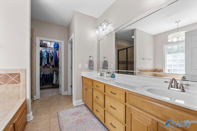bathroom with tile patterned flooring, a sink, double vanity, and a shower stall